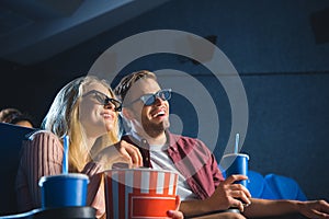 cheerful couple in 3d glasses with popcorn watching film together photo