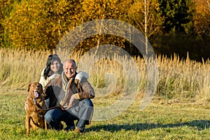 Cheerful couple with dog in autumn countryside