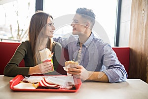 Cheerful Couple in eating burgers fast food Reastaurant