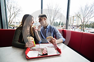 Cheerful Couple in eating burgers fast food Reastaurant