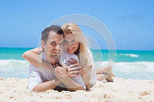 Cheerful couple embracing and lying on the beach o