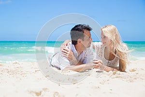 Cheerful couple embracing and lying on the beach o