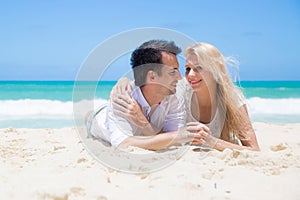 Cheerful couple embracing and lying on the beach on a sunny day