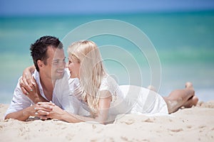 Cheerful couple embracing and lying on the beach on a sunny day
