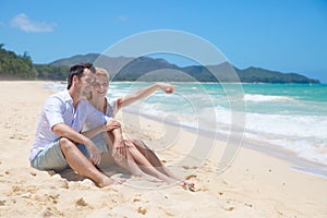 Cheerful couple embracing and posing on the beach