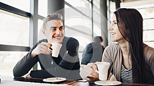 Cheerful couple enjoying coffee together in modern cafe.Drinking hot caffeine beverage on a break with business partner