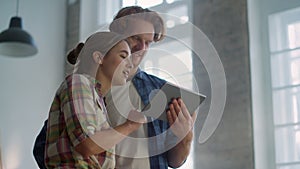 Cheerful couple enjoying design of house renovation with tablet indoors.