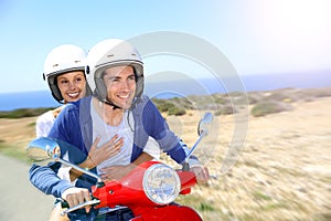 Cheerful couple enjoying scooter ride in the islands