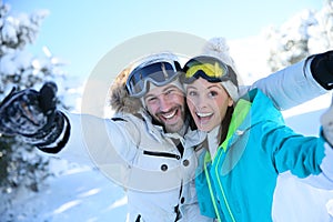 Cheerful couple enjoying their winter holidays on ski slopes