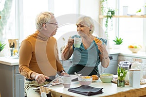 Cheerful couple having breakfast and chatting at the kitchen table