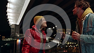 Cheerful couple having fun outdoor. Man and woman fooling with burgers in city.