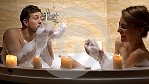 Cheerful couple having fun playing with water and foam in whirlpool, romance