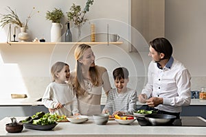 Cheerful couple of parents and two kids cooking fresh food