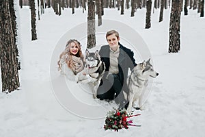 Cheerful couple are playing with siberian husky in snowy forest. Winter wedding Artwork