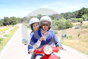 Cheerful couple on red moto visiting island