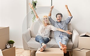 Cheerful Couple Relaxing On Sofa Celebrating Moving To New House