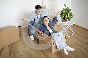 Cheerful Couple Riding Inside Cardboard Box While Having Fun On Moving Day