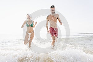 Cheerful couple running at the beach
