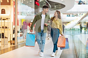 Cheerful Couple Shopping Walking Carrying Shopper Bags In Mall