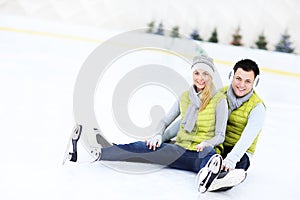 Cheerful couple sitting on the skating rink