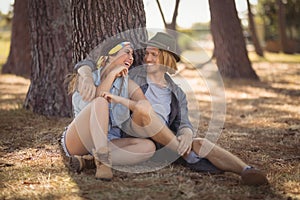 Cheerful couple sitting by tree trunk