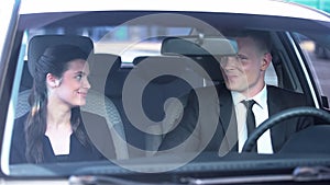 Cheerful couple smiling and looking flirtatiously in car, romance on first date