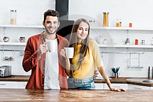 Cheerful couple standing in kitchen and smiling