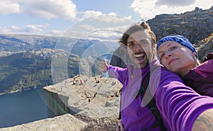 A cheerful couple in the summit of the Pulpit Rock Preikestolen, one of the world`s most spectacular viewing points. A plateau