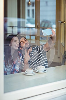 Cheerful couple taking selfie at cafeteria