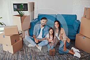 Cheerful couple and their child posing in their new house
