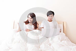 Cheerful couple using touch pad in bed