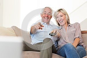 Cheerful couple watching tv at home