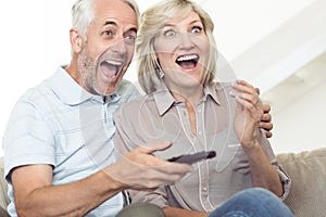 Cheerful couple watching tv on sofa