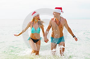 Couple wearing Santa hats on the beach