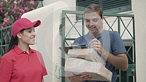 Cheerful courier girl in red cap delivering package