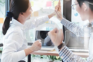 Cheerful coworkers high fiving in creative office