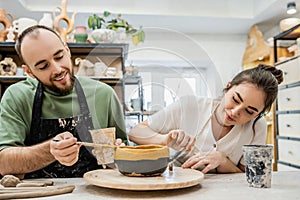 Cheerful craftspeople in aprons coloring clay