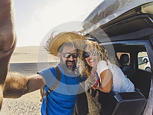 Cheerful crazy adult cacuasian couple enjoy the travel together with car and tent on the roof taking selfie picture with action
