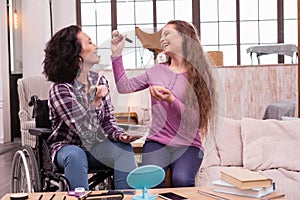 Cheerful crippled woman and girl having fun during makeup