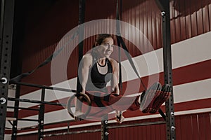 Cheerful crossfit woman doing abs exercises on gymnastic rings photo