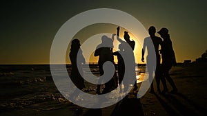 Cheerful crowd dancing on the beach. They jump in the sun. People are having fun. They are happy. Silhouettes of people
