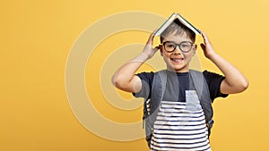 Cheerful cute boy schooler with book on his head