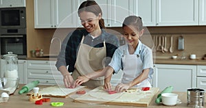 Cheerful cute child girl and happy mom preparing homemade cookies