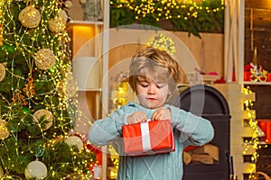 Cheerful cute child opening a Christmas present. Happy child decorating Christmas tree. Cute little child near Christmas