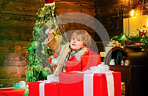 Cheerful cute child opening a Christmas present. Happy child with Christmas gift box. Winter kid. Funny kid holding