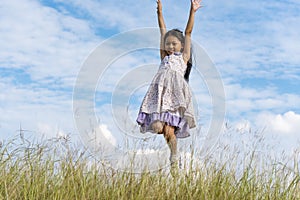 Cheerful cute girl holding balloons running on green meadow white cloud and blue sky with happiness. Hands holding vibrant air