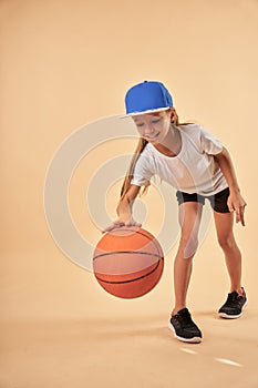 Cheerful cute girl in sportswear playing basketball