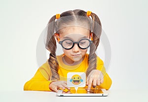 Cheerful cute little girl with glasses using tablet computer on white background. Social media concept.