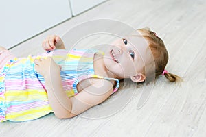 Cheerful cute little girl lying on the floor in the children`s