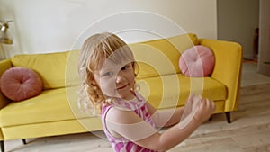 cheerful and cute preschool girl jumps and dance in living room. cool child in bright pink dress is having fun at home